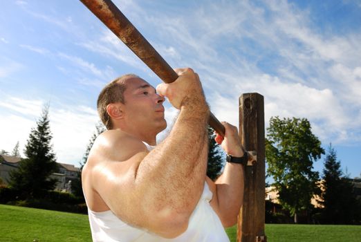Strong Man Doing Pullups in the Park on a Sunny Day