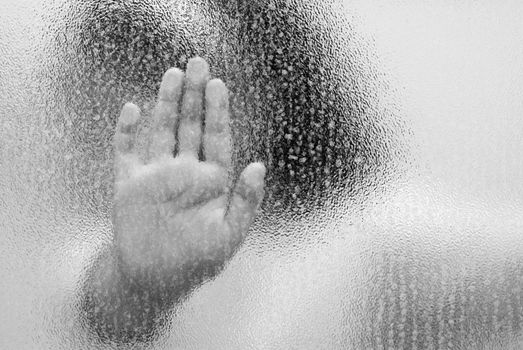 A trapped child with her hand on the glass, shot in black and white