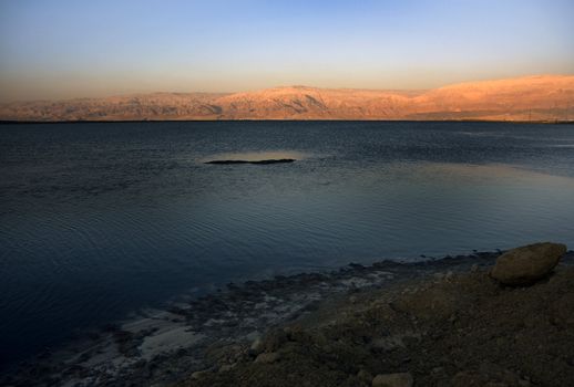 The water of the dead sea with the Jordan mountains at sunset