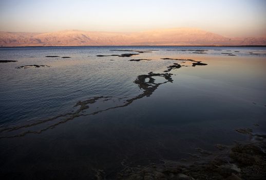 The water of the dead sea with the Jordan mountains at sunset