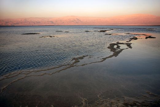 The water of the dead sea with the Jordan mountains at sunset