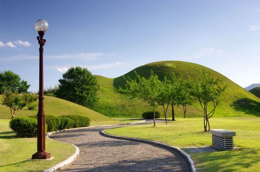 A pathway leading to royal burial tombs from the Silla Dynasty dating back a thousand years. Kyeongju, South Korea.  
 
