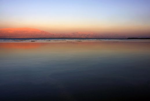 The water of the dead sea with the Jordan mountains and salty islands  at sunset