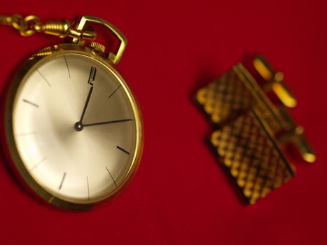 gold pocket watch and cuff links on red velvet