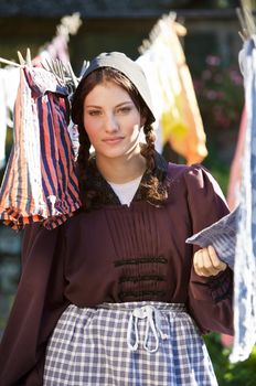 Farm girl in old fashioned clothes checking the laundry