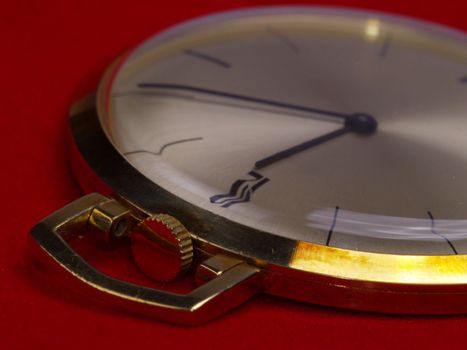 detail of gold pocket watch on red velvet