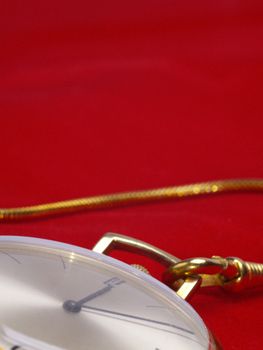 detail of gold pocket watch on red velvet