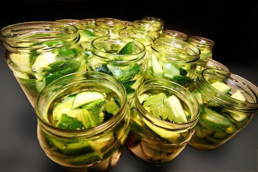 Glass jars filled with delicious green and tasty preserved cucumbers