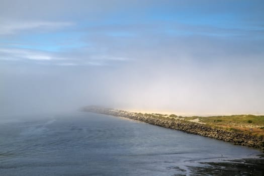 Blue sky and fog over a sandy beach breaker