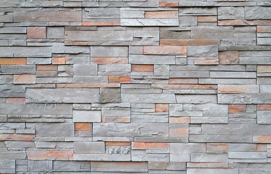Gray, brown, red flat stone wall in a random pattern