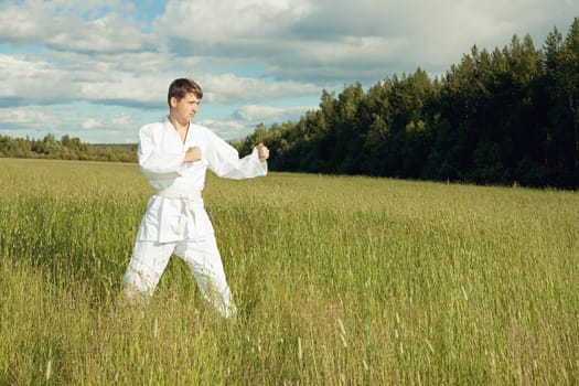 The man in a kimono trains karate in the open air