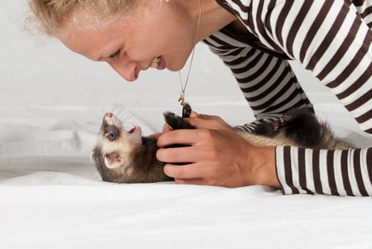 Woman playing with polecat in studio on white background