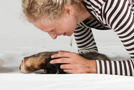 Woman playing with polecat in studio on white background