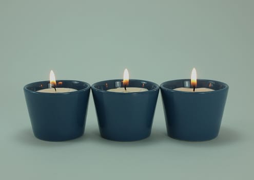 Three lighted candles in blue holder