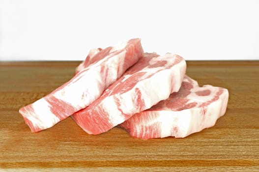 Three slices of pork chops on a wooden cutting board.