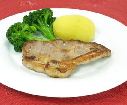 A plate of fried pork chop with boiled broccoli and potato.