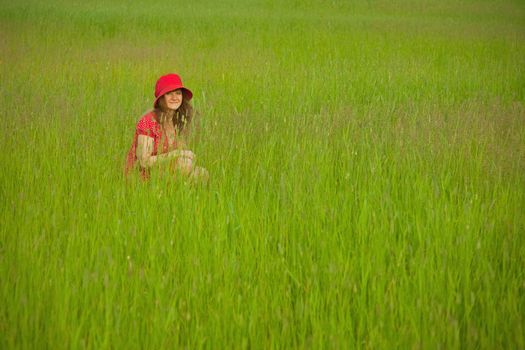The woman in red clothes sits in a green grass