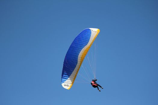 A yellow and blue paragliding in the sky