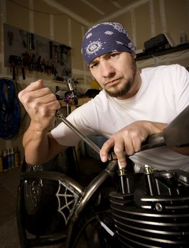 Hispanic mechanic working on a chopper style motorcycle