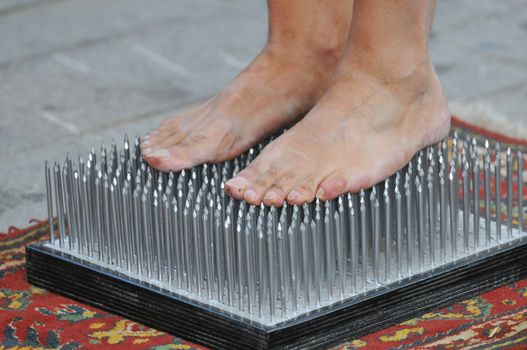 Fakir foots standing on a nails bed