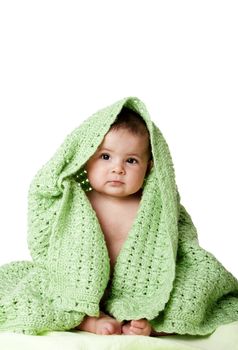 Beautiful cute innocent Caucasian Hispanic baby face while sitting and covered between green knitted blankets, isolated.