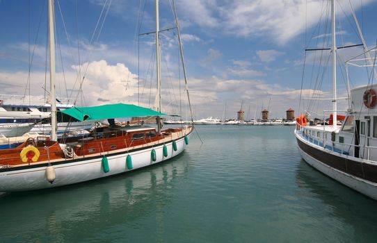 Yachts and the three old mills of the old harbor of Rhodes, Greece