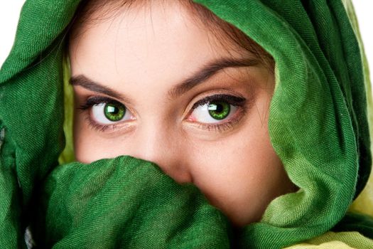 Portrait of mysterious beautiful Caucasian Hispanic Latina woman face with green penetrating eyes and green fashion scarf wrapped around head and mouth covered, isolated.