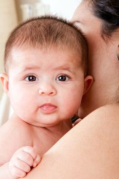 Caucasian Hispanic Latina mother holding cute baby. Infant face with twinkly eyes and drooling.