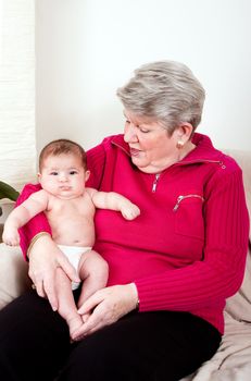 Grandma sitting on couch in livingroom with baby infant on lap.