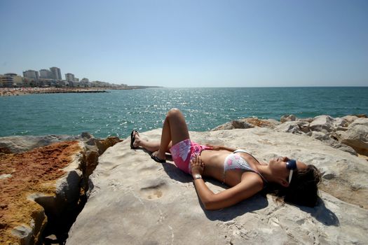 sexy woman on bikini tanning on the coast