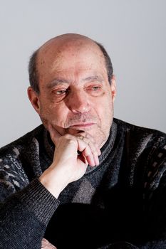 Face of an old man with little hair and bald spot and hand on his chin with serious expression, isolated.