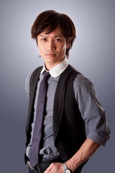 Assertive confident successful casual Asian business man, wearing vest and tie, with firm look, isolated.