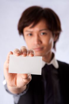 Blurred Asian business man holding and presenting a blank white card. Sales representative introducing himself.