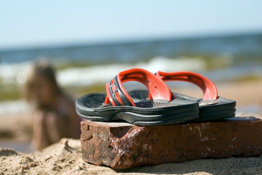 Pair of plastic beach slippers at the seashore