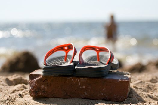 Pair of plastic beach slippers at the seashore