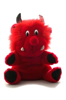 A soft toy little red devil sitting and smiling