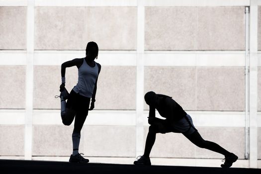 Two female friends stretching before a run.