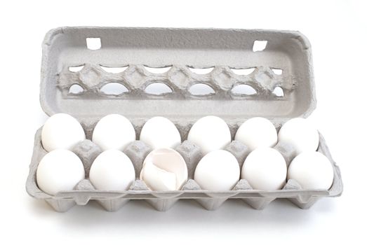 A carton of white eggs with one egg used.