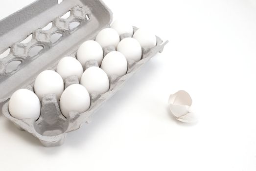 A carton of white eggs with one egg used.