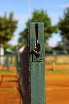 Close up of the side of a tennis net on a clay court