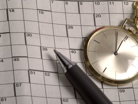 pocket watch and pen on crossword puzzle
