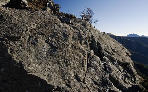 A cute stone was standing on a rock wall, it seems looking at the mountain far away.