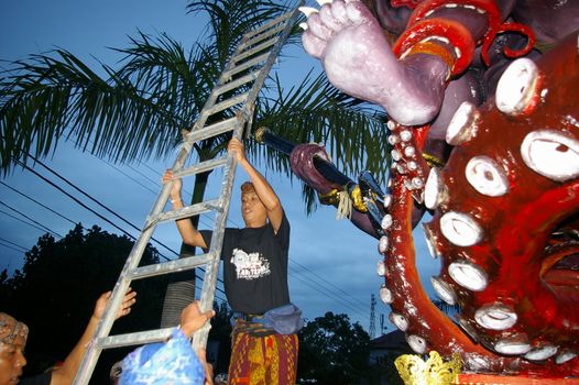 Setting up a ladder to climb a giant statue at the Balinese Hindu festival of Pengrupukan, in Nusa Dua, Bali, March 15, 2008. The annual festival is to roust out the devils which have gone into hiding on the island.