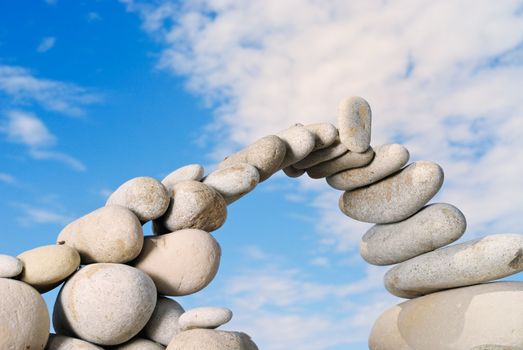 Sea pebble combined in the form of the bridge against the sky