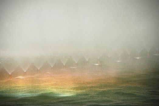 rainbow in the background of the spray from the fountain