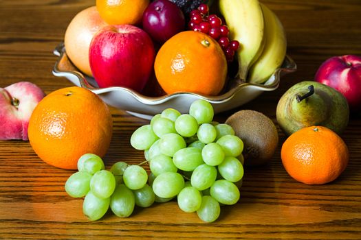 Selection of colorful, fresh, natural looking fruit in an old bowl placed on wood.