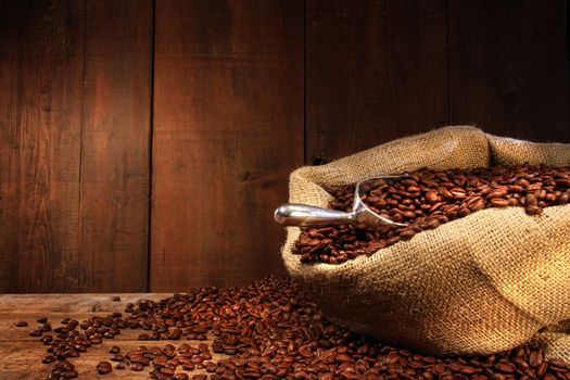 Burlap sack of coffee beans against dark wood background