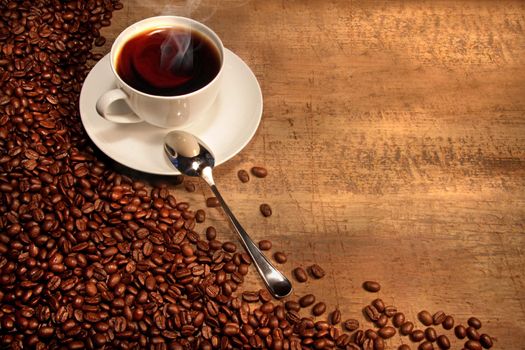 White coffee cup with beans on rustic wooden table 