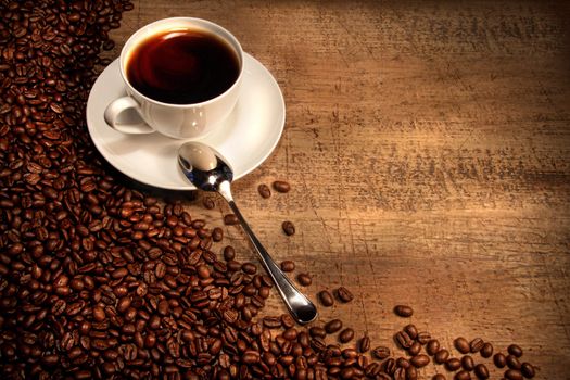 White coffee cup with beans on rustic wooden table 