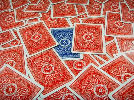 Blue coloured playing card surrounded by red coloured playing cards